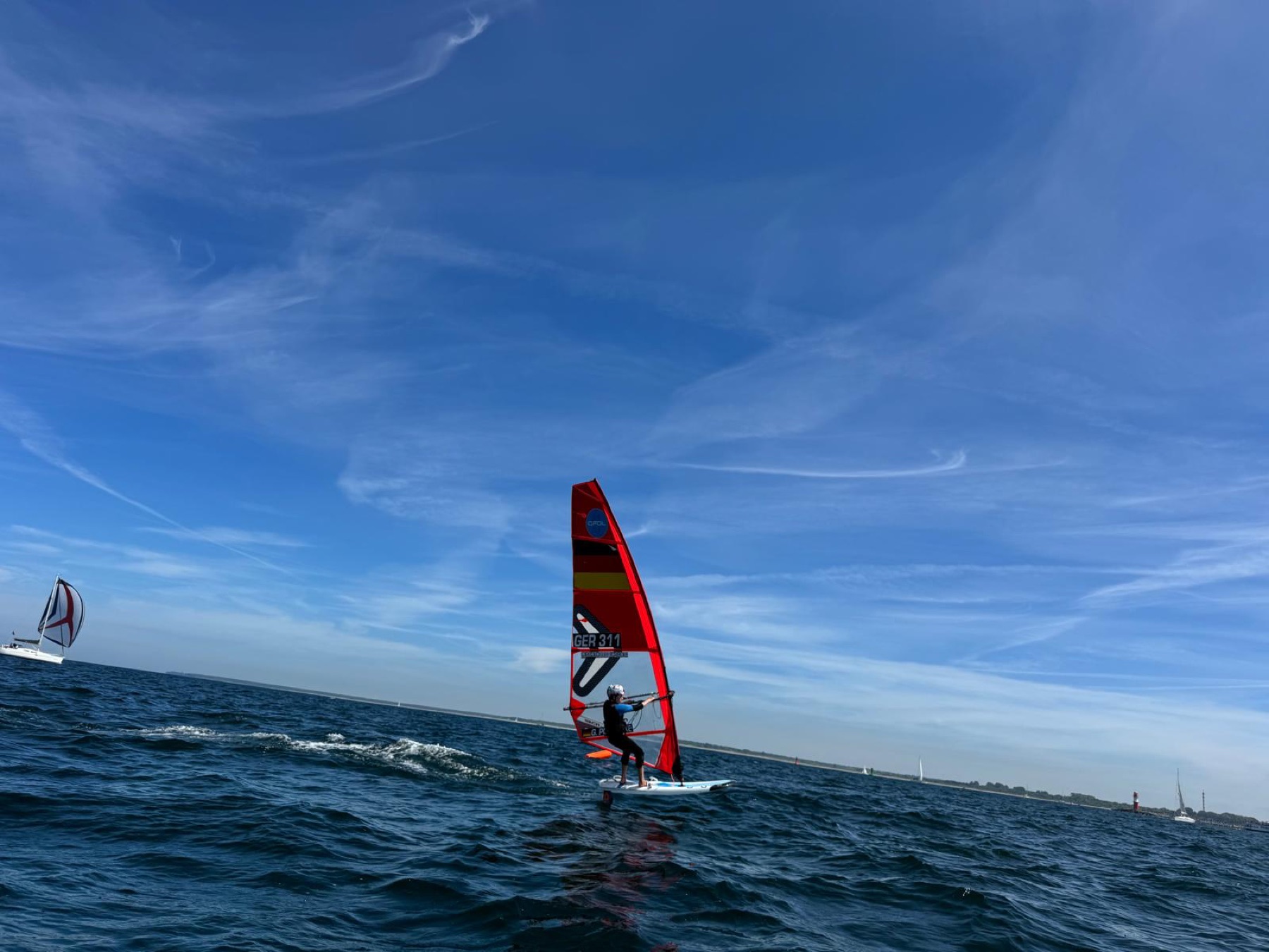 Theo Siemann racing upwind on his iQFOiL board under a wide blue sky
