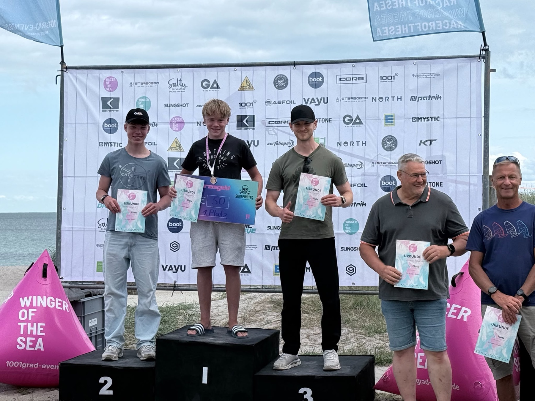 Theo Siemann on the podium with his prize-money certificate for 1st place, Rookie-Foil Mixed, Racer of the Sea Kellenhusen 2026